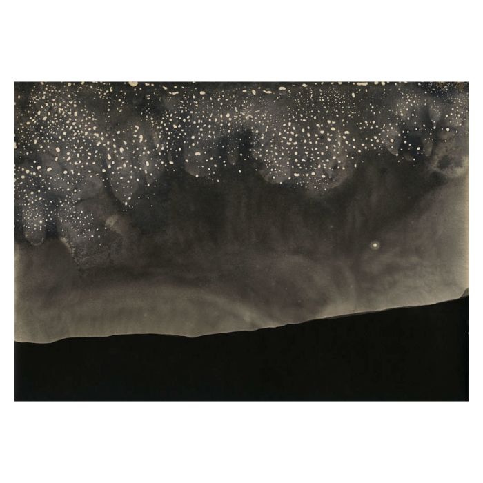 Tirage d’Alison Rossiter sur papier photographique périmé : un ciel de taches claires sur fond sombre au-dessus d’une ligne noire qui évoque un relief.
