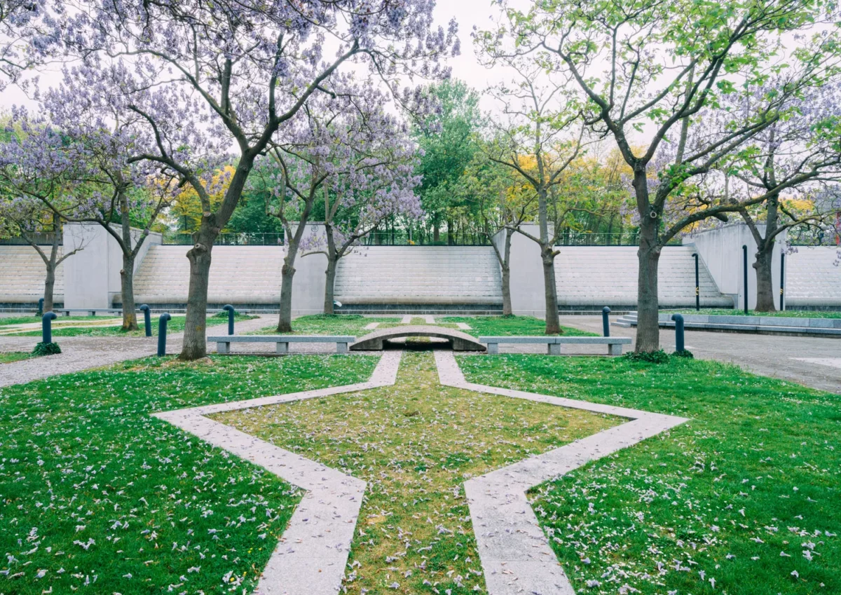 Allée paysagère symétrique avec pelouses, arbres en fleurs et petit pont au parc de la Villette à Paris, photo d’architecture paysagère réalisée par photographe à Paris