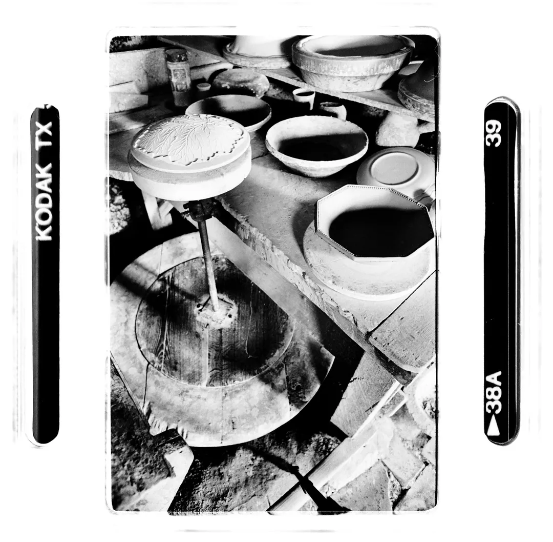 Photo noir et blanc de l’atelier de poterie au poët-laval (Drôme) montrant un tour, des bols et moules en cours de fabrication, réalisée dans le cadre du reportage sur la poterie traditionnelle en terre blanche.