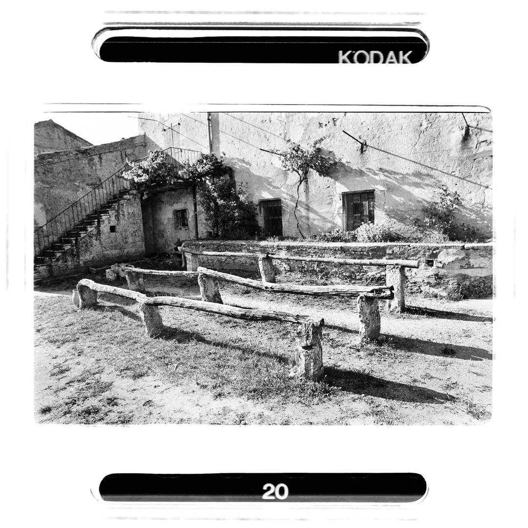 Photo noir et blanc d’un ancien bâti au poët-laval dans la Drôme, avec structures en bois et escalier extérieur, réalisée lors du reportage sur le potier Jacky Robin travaillant la terre blanche du village de poterie.