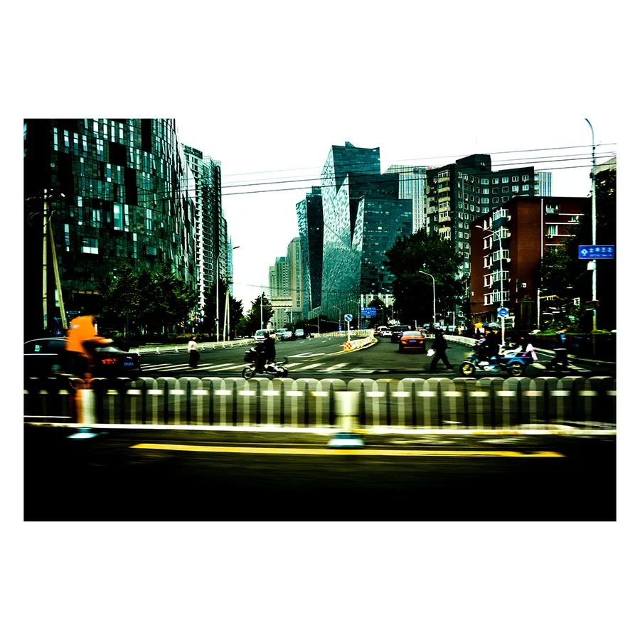 Déambulation sur une avenue de Pékin bordée de tours, capturée dans un flou de mouvement aux teintes vertes.