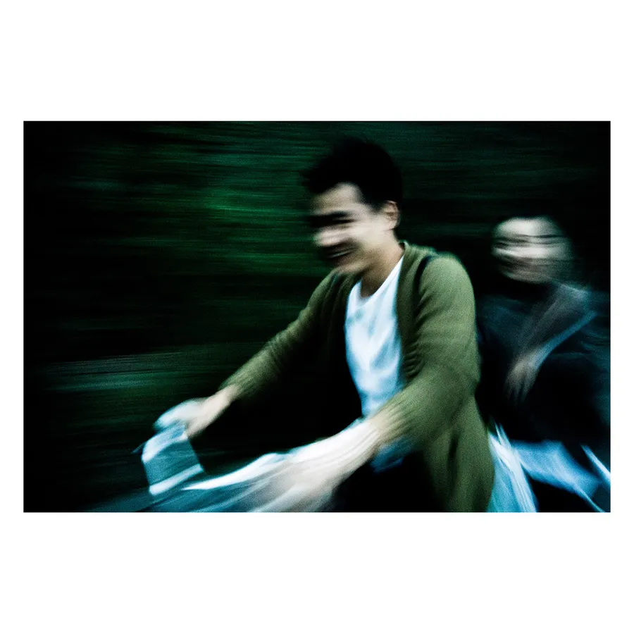 Piéton saisi dans un flou de mouvement nocturne, illustrant l'énergie cinétique de la ville.