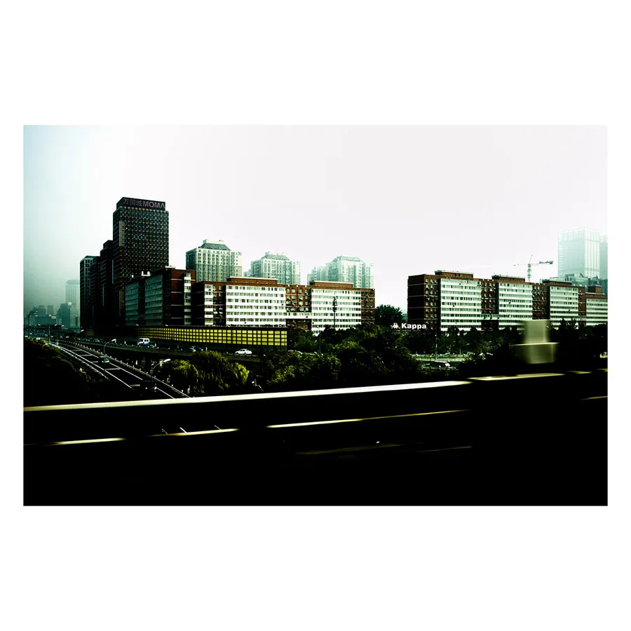 Paysage urbain typique de Pékin avec alignement de tours résidentielles vues depuis l'autoroute périphérique, dans un rendu evanescent.