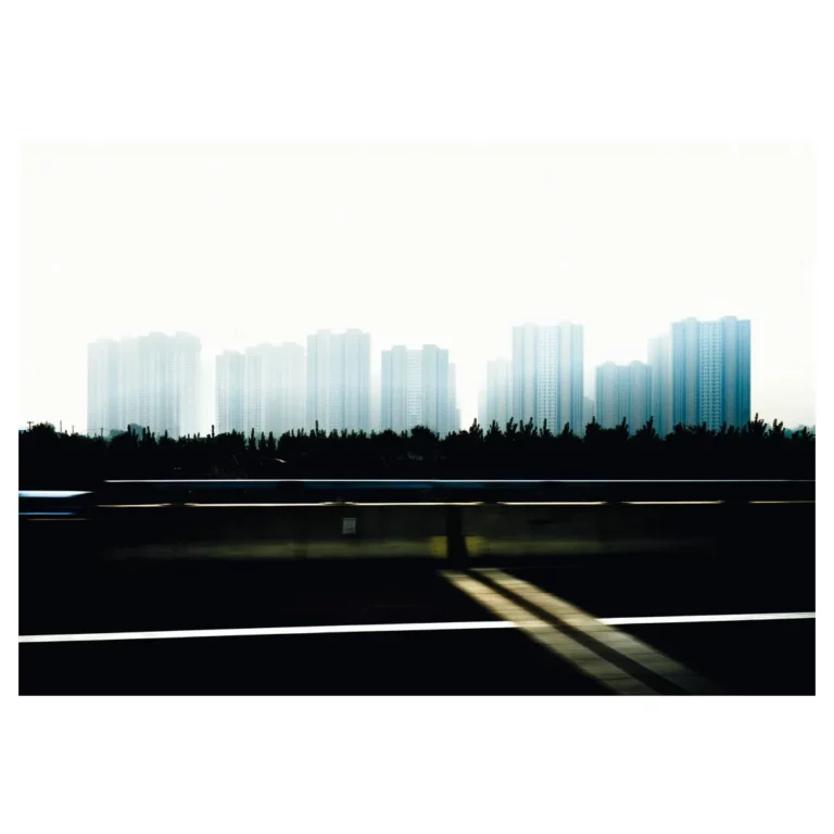 Vue floue du skyline urbain de Pékin depuis une autoroute, capturant l'essence onirique de la ville en mouvement, et de ses zones d’habitation de masses.