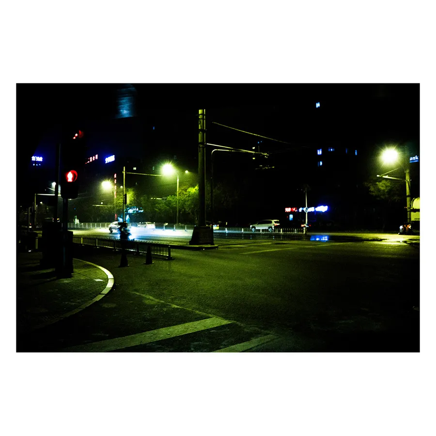 Alignement de lampadaires créant une perspective avec des halos lumineux dans l'espace urbain nocturne de Pékin.