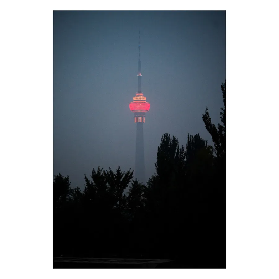 Vue sur la tour centrale de radio-télédiffusion pékinoise enveloppée dans une atmosphère crépusculaire mystérieuse et onirique.