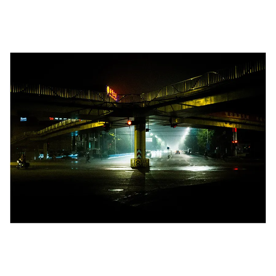 Atmosphère onirique d'une rue pékinoise après la pluie, avec reflets lumineux sur l'asphalte.