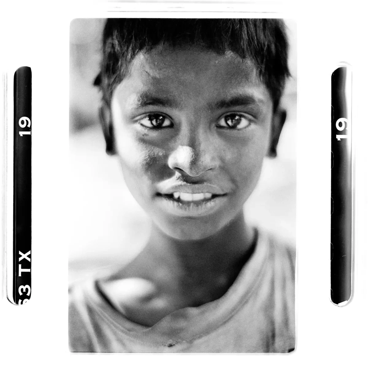 Portrait garçon adolescent des rues regardant le photographe, en Inde pour une photographie humaniste en noir et blanc.