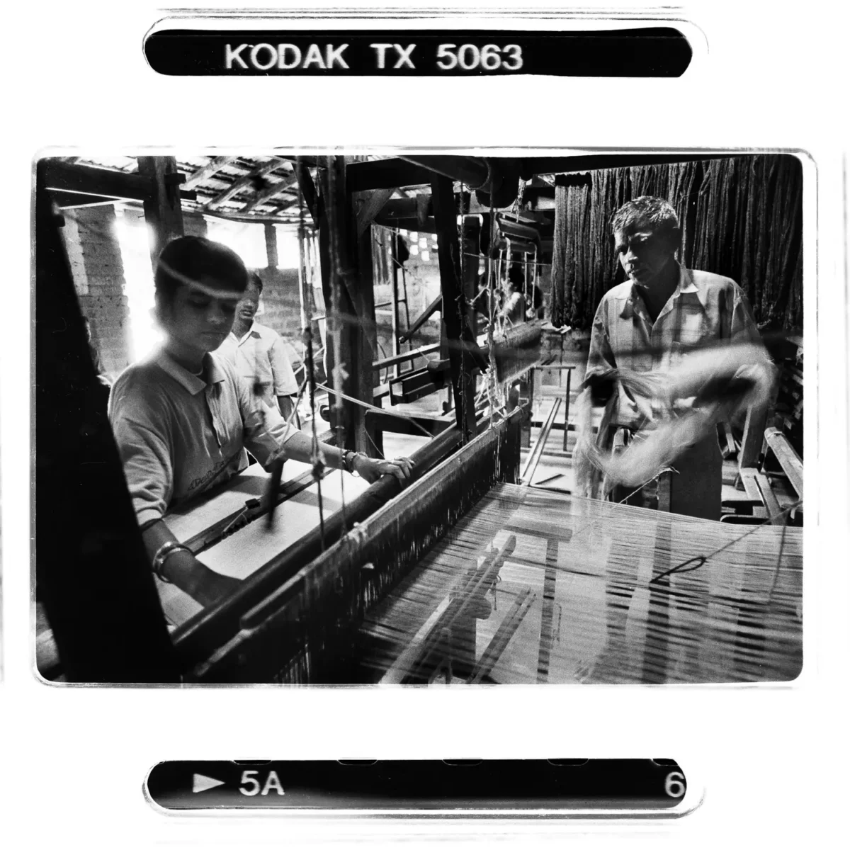 Scène de vie intérieure avec un atelier de tissage pour une enfant des rues en Inde. Photoreportage en noir et blanc.