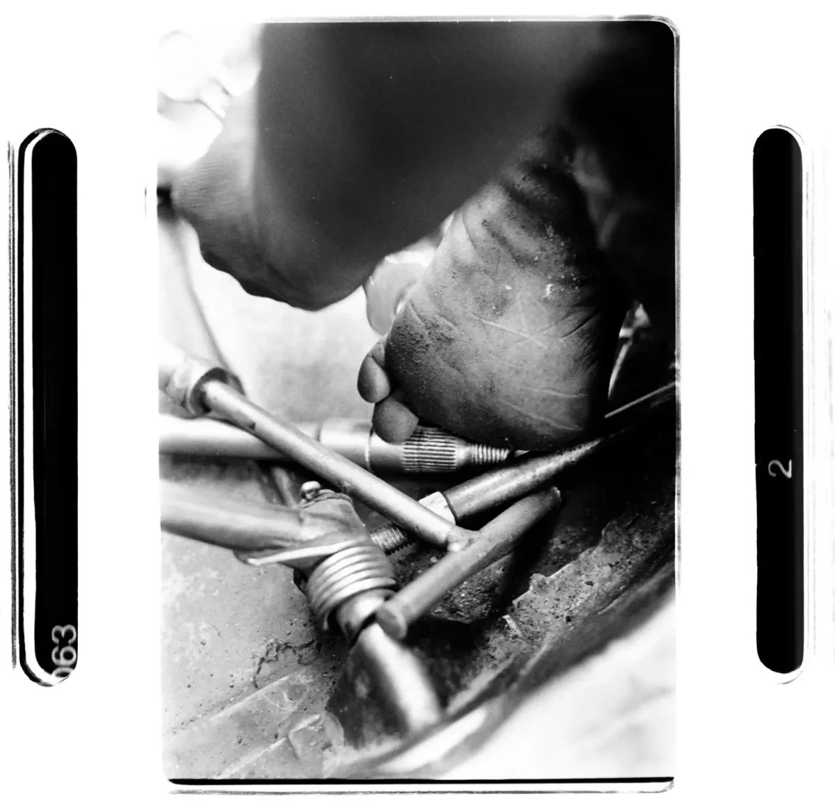 Enfant au travail forcé rue Inde avec un gros plan de pied dans dans outils de mécanicien pour une photographie sociale en noir et blanc