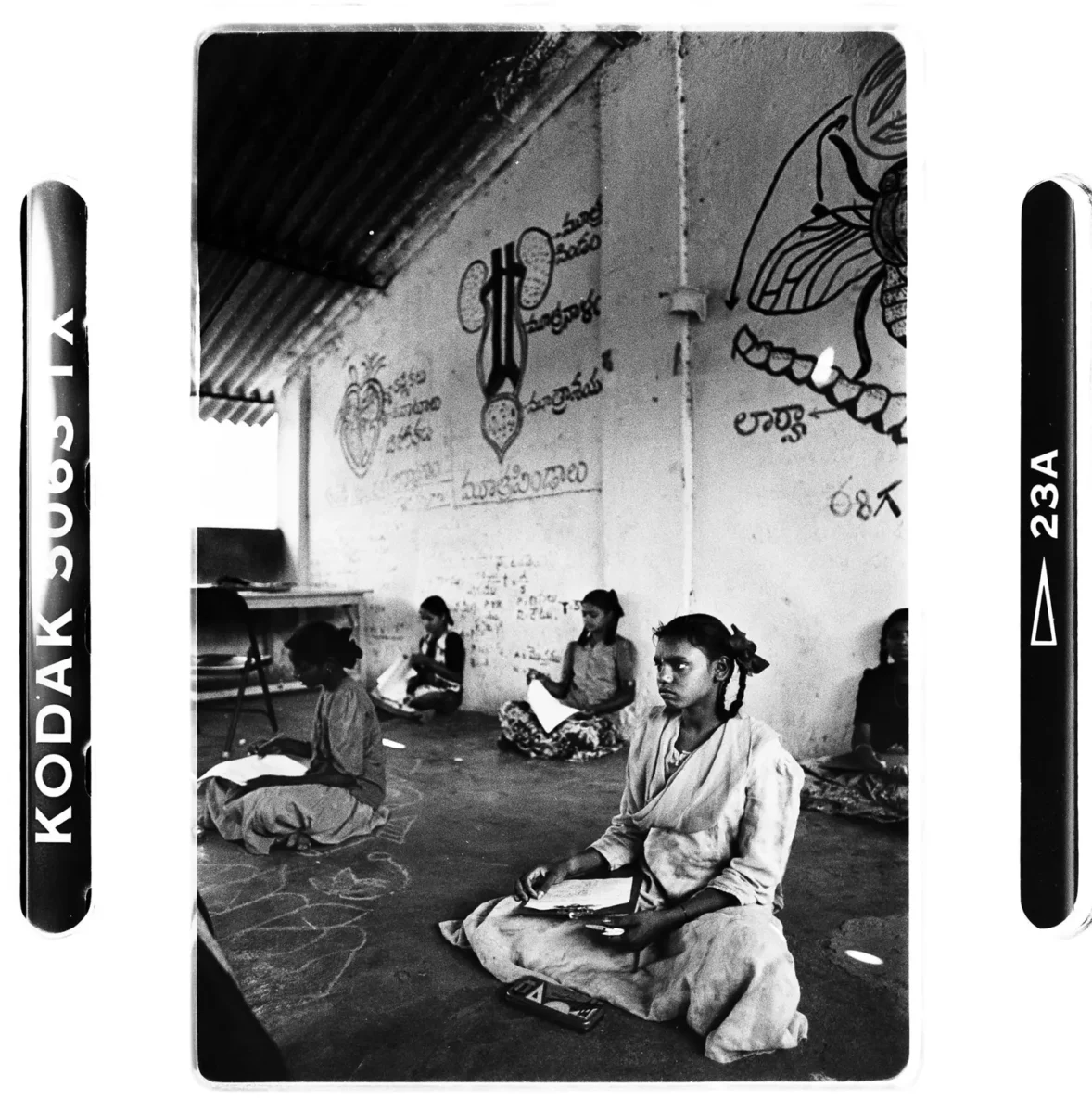 Jeune fille assise sur une estrade avec plusieurs camarades à l'école en Inde pour une photographie documentaire.