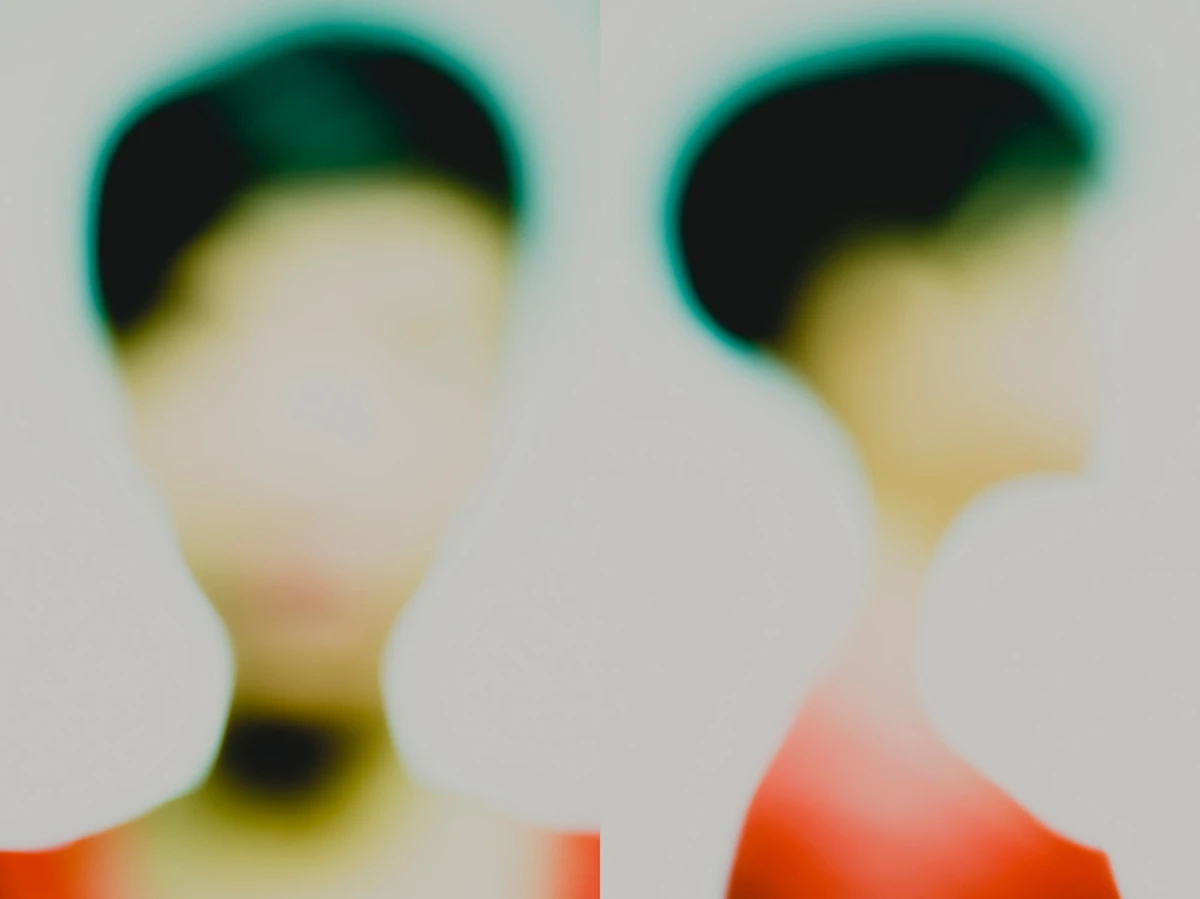 Photographie défocalisée en diptyque : à gauche, visage de face très flou ; à droite, profil droit aux cheveux courts foncés cerclés d’un halo vert, vêtement rouge en bas de cadre, fond clair high-key, identité volontairement estompée — série « Erasure ».