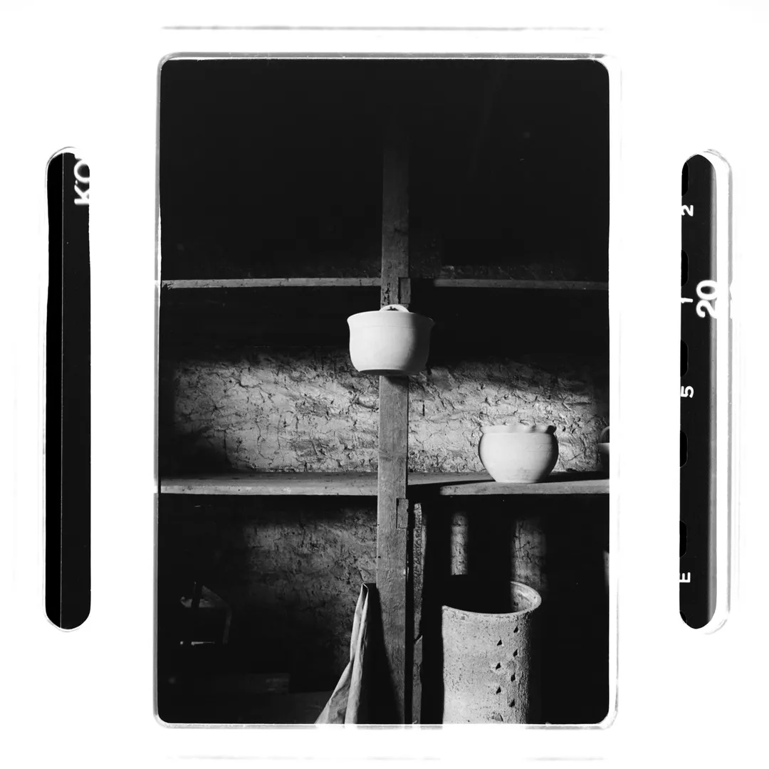 Photographie noir et blanc d’une étagère en bois dans un atelier de poterie au poët-laval (Drôme) avec pots en terre blanche en cours de séchage, réalisée pour un reportage sur la poterie traditionnelle du village.