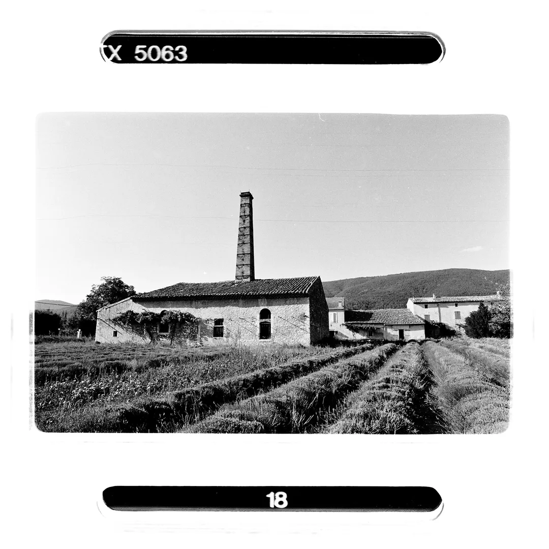 Photographie noir et blanc de la grande cheminée de l’ancienne fabrique à Dieulefit (Drôme), au cœur du village historique de poterie, réalisée lors d’un reportage sur le potier Jacky Robin utilisant la terre blanche locale.
