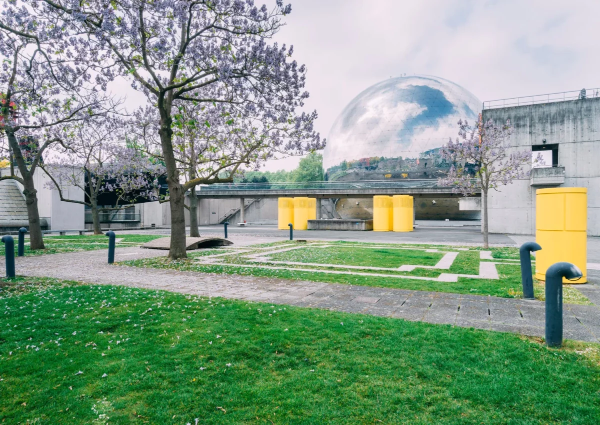 Jardin du parc de la Villette à Paris avec arbres en fleurs, allées géométriques et vue sur la Géode de la Cité des sciences, photographie d’architecture extérieure par photographe à Paris