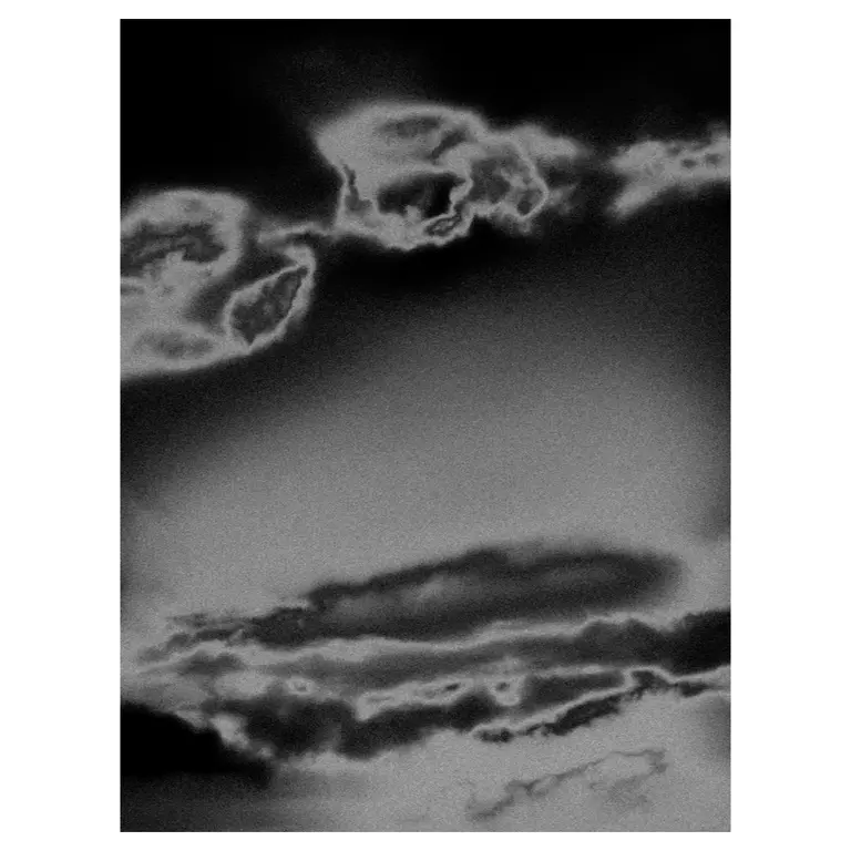 Photographie artistique en noir et blanc d’un ciel orageux : nuages texturés aux contours lumineux, ambiance abstraite, ciel orageux aux formes vaporeuses.