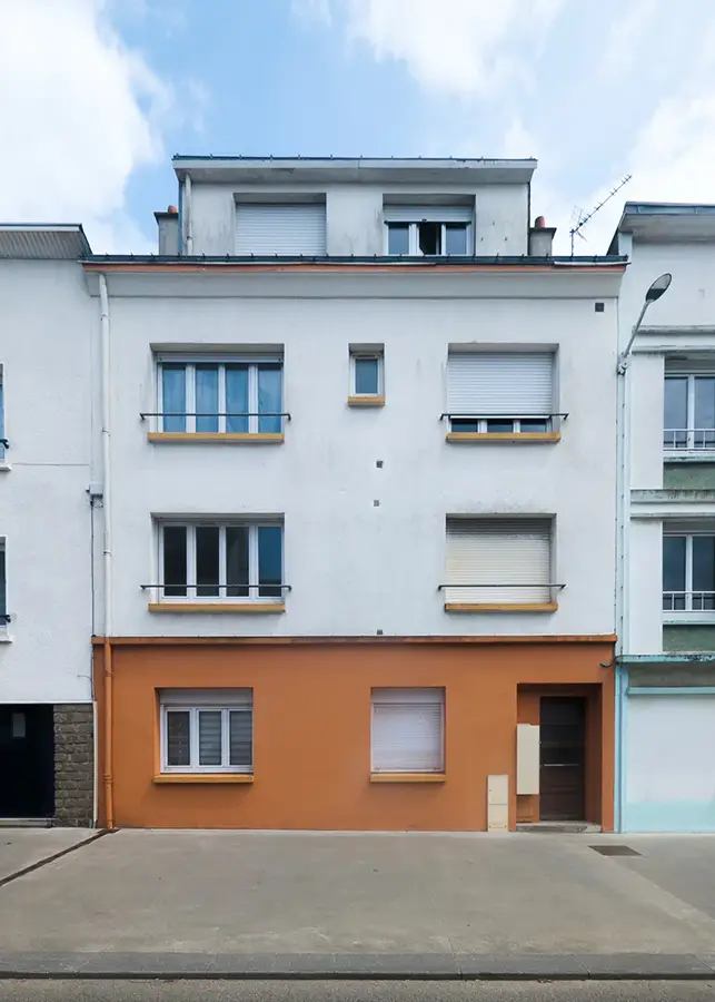Photographie d’architecture d’une façade urbaine avec rez-de-chaussée orange et étages blancs, réalisée à Saint Nazaire.