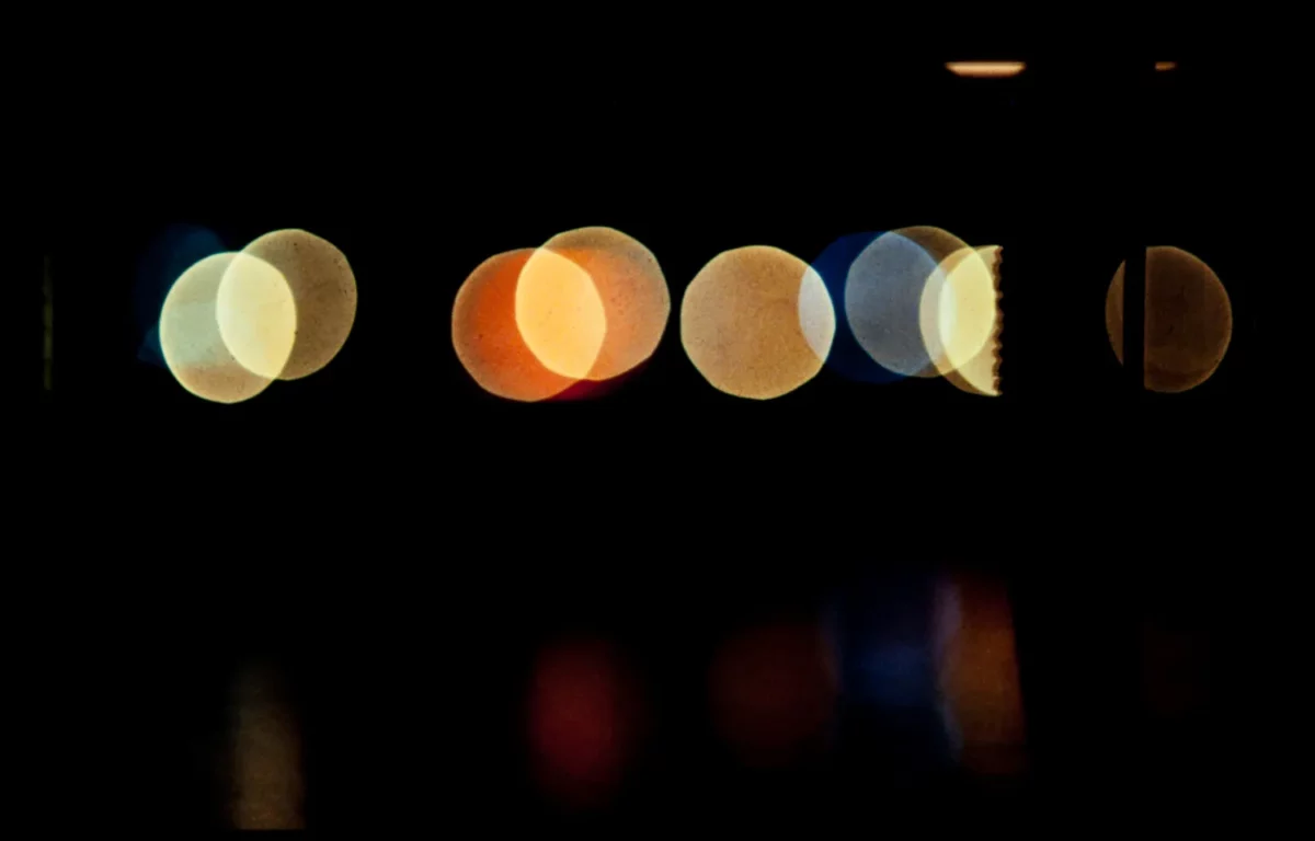 Photographie abstraite de lumières urbaines en bokeh coloré sur fond noir, réalisée par un photographe professionnel à Pariis.