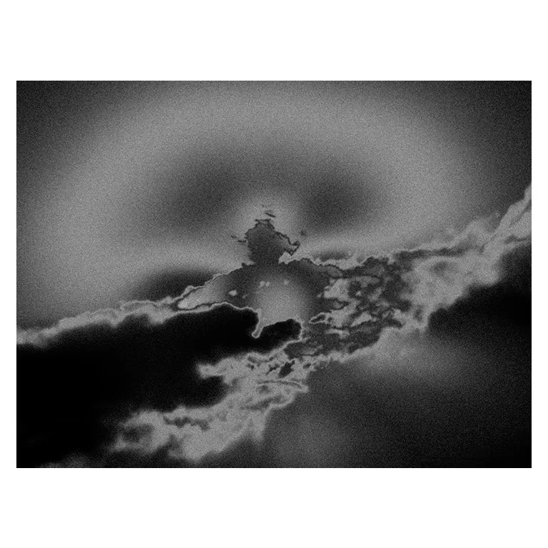 Ciel avec un effet de halo en NB, avec une masse nuageuse centrale avec liserés lumineux et dégradés doux dans un effet de photographie atmosphérique de bord de mer, poétique.