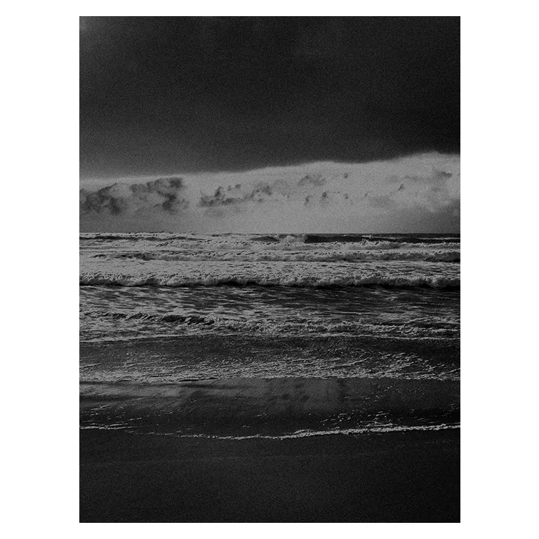 Photographie noir et blanc d’une mer agitée : vagues superposées, ciel orageux, reflets sur le sable avec un rendu très contrasté au Porge près de Lacanau; un partie pris d’un rendu pictural plasticien.