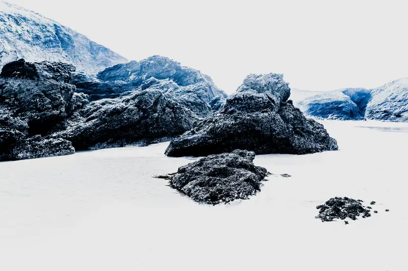 Îlots rocheux dans brume bleutée et lagune de sable, à Belle-Île-en-Mer – lumière froide, paysage photographique contemporain.