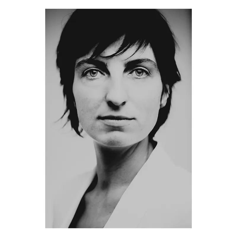 Portrait en studio d'une femme aux cheveux courts, des yeux lumineux, claire dans une lumière douce et naturelle, exploration de la féminité contemporaine, photographie noir et blanc intemporelle.