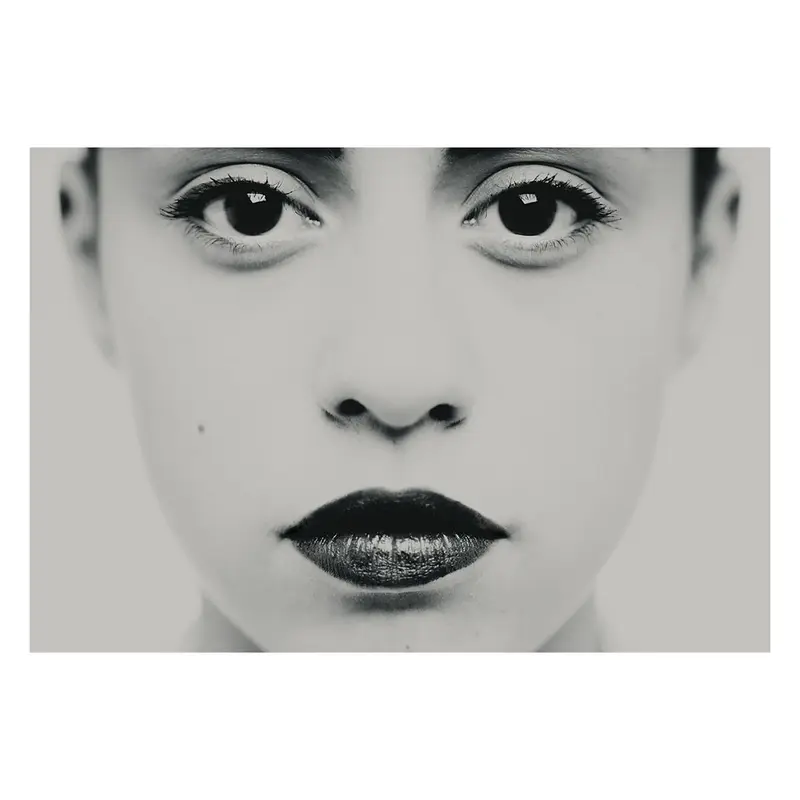 Photographie en très gros plan centrée sur les yeux et le regard, travail plastique sur l'intensité et la frontalité, détail d'un portrait en studio noir et blanc.