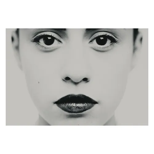 Photographie en très gros plan centrée sur les yeux et le regard, travail plastique sur l'intensité et la frontalité, détail d'un portrait en studio noir et blanc.