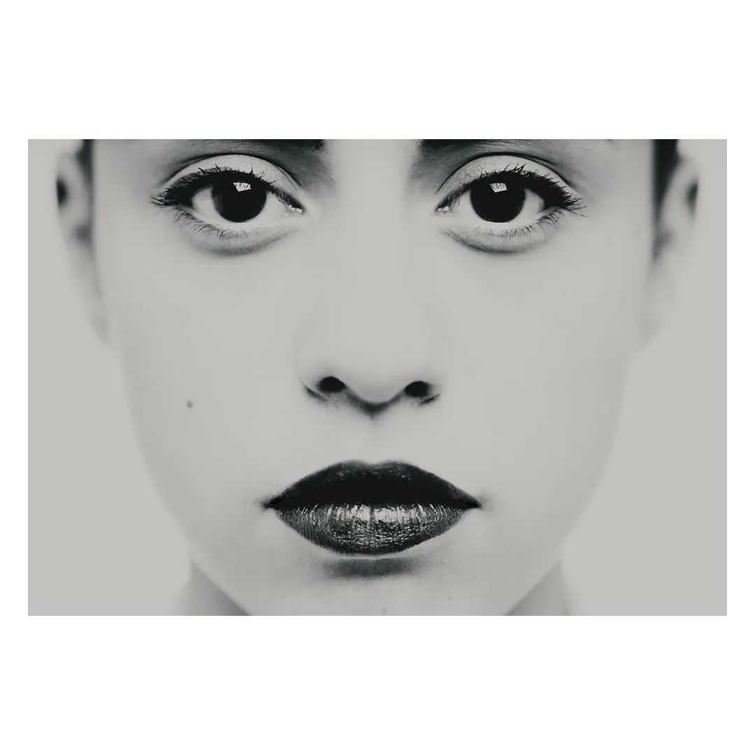 Photographie en très gros plan centrée sur les yeux et le regard, travail plastique sur l'intensité et la frontalité, détail d'un portrait en studio noir et blanc.