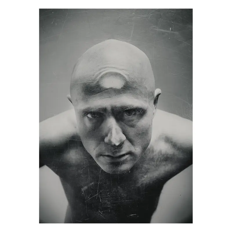 Photographie plasticienne d'un portrait d'homme au crâne rasé, regard dirigé vers le photographe, étude sur la vulnérabilité et la présence corporelle en studio photo.