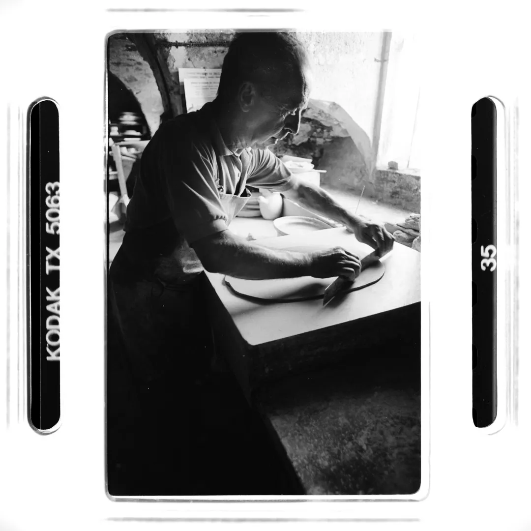 Photo noir et blanc d’un potier au travail dans son atelier au poët-laval (Drôme), façonnant une pièce de terre blanche près d’une fenêtre, réalisée pour un reportage sur la poterie traditionnelle du village.