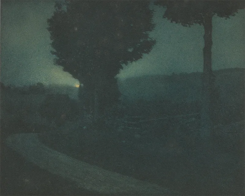 Photographie pictorialiste d'Edward Steichen représentant une route sinueuse dans un vallon sous la lueur d'un clair de lune, aux tons vert et bleu profonds.