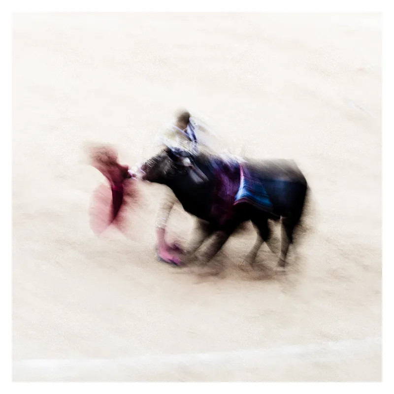 Photographie artistique de corrida à Bayonne avec effet de flou cinétique capturant le mouvement du taureau noir et du torero, cape rose en mouvement, tons violets et bleus, style Ernst Haas