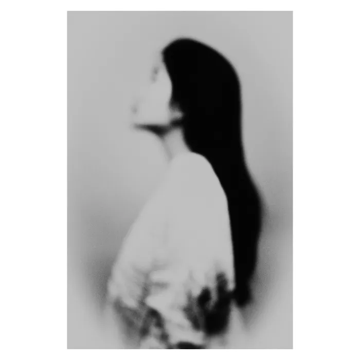 Portrait de profil en noir et blanc avec un flou artistique vaporeux, silhouette féminine aux cheveux longs regardant vers le haut, esthétique onirique et minimaliste, photographie de studio réalisée au Vésinet par Nicolas Louis.