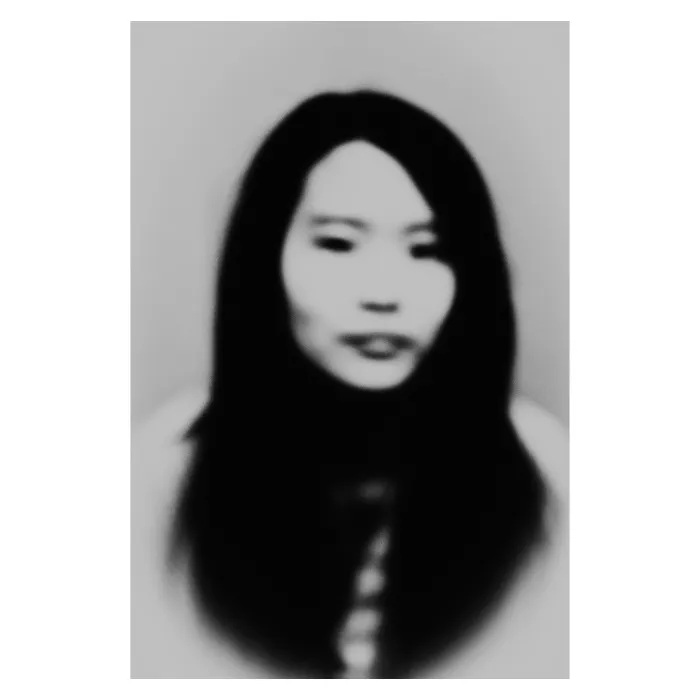 Portrait de face en noir et blanc avec un flou artistique vaporeux, visage féminin aux cheveux longs et sombres, esthétique onirique et minimaliste, photographie de studio réalisée au Vésinet par Nicolas Louis.