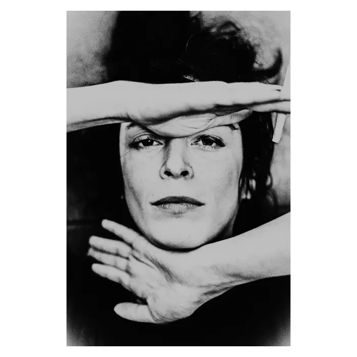 Portrait artistique en noir et blanc d'une femme au regard frontal, visage partiellement masqué par les mains dans une composition graphique, grain argentique marqué et contraste élevé, photographie de studio réalisée au Vésinet par Nicolas Louis.