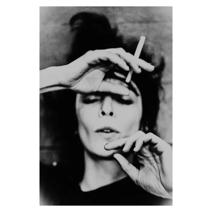 Portrait artistique en noir et blanc d'une femme encadrant son visage avec ses mains, style argentique au grain marqué, regard frontal intense, photographie de studio réalisée au Vésinet par Nicolas Louis.