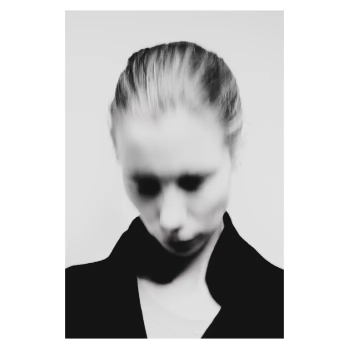 Portrait d'art en noir et blanc d'une femme à la tête inclinée, effet de flou de mouvement (motion blur) créant une silhouette évanescente et onirique, photographie de studio réalisée à Bagnolet par Nicolas Louis.
