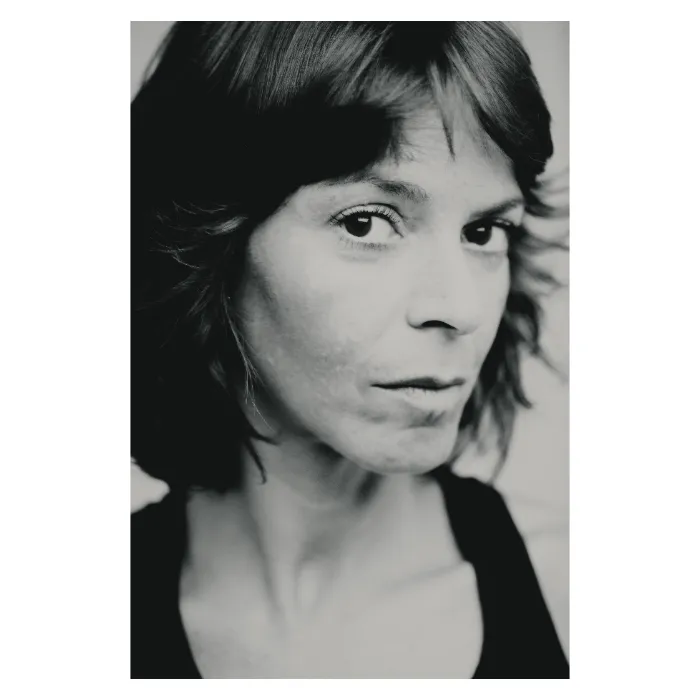 Portrait de face en noir et blanc d'une femme au regard intense et direct, cadrage serré sur le visage mettant en valeur une expression sérieuse et naturelle, photographie de studio réalisée à Paris par Nicolas Louis.