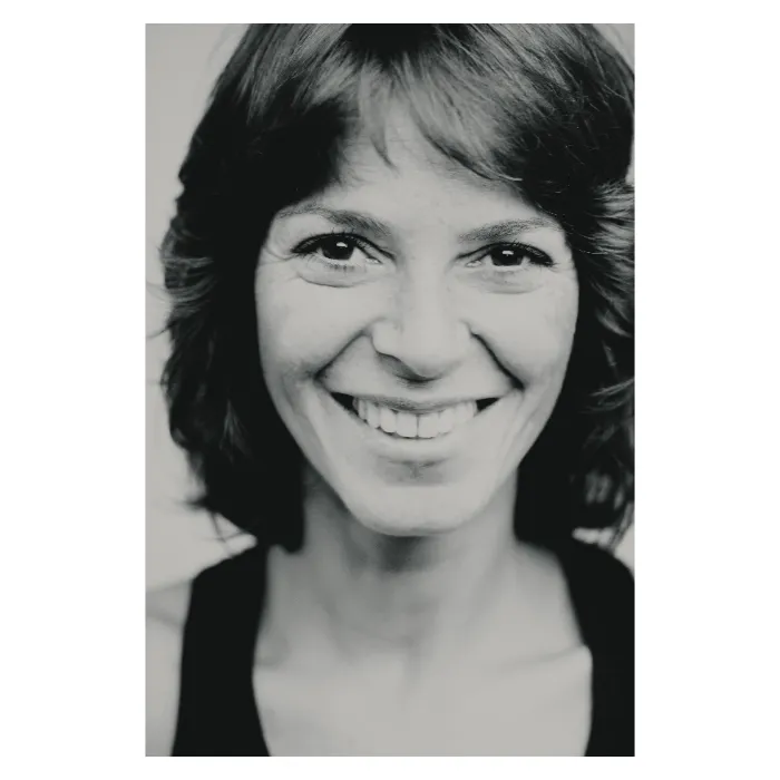 Portrait serré en noir et blanc d'une femme au regard de trois-quarts mystérieux, cheveux châtains mi-longs, éclairage de studio doux soulignant les traits du visage, photographie réalisée à Paris par Nicolas Louis.