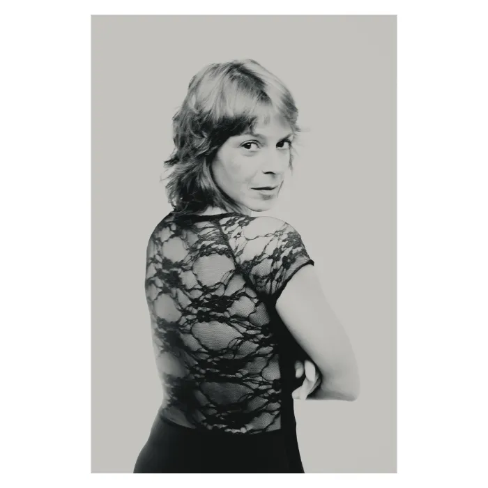 Portrait artistique féminin en noir et blanc, vue de dos avec regard par-dessus l'épaule, femme portant un haut en dentelle noire transparente, photographie de studio réalisée à Paris par Nicolas Louis.