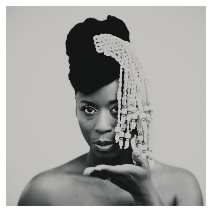 Portrait artistique en noir et blanc de Fafa Ruffino, coiffe traditionnelle perlée et regard captivant, photographie de studio Le Vésinet par Nicolas Louis.