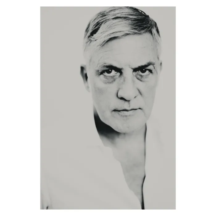 Portrait d'art masculin en noir et blanc, visage cadré en plan serré d'un homme mûr aux cheveux blancs, regard perçant et direct, photographie de studio réalisée à Bagnolet par Nicolas Louis.