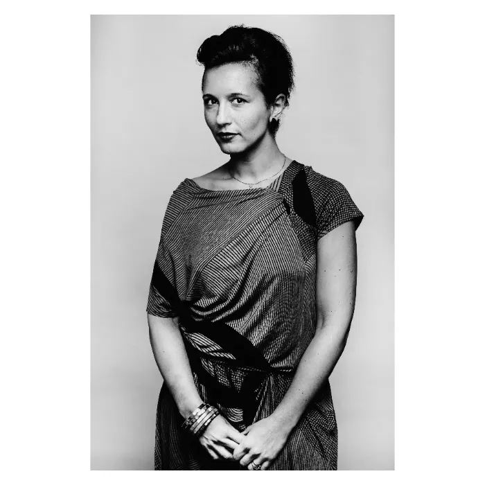 Portrait artistique en noir et blanc d'une femme en robe texturée, mains croisées et regard direct, photographie de studio réalisée au Vésinet par Nicolas Louis.