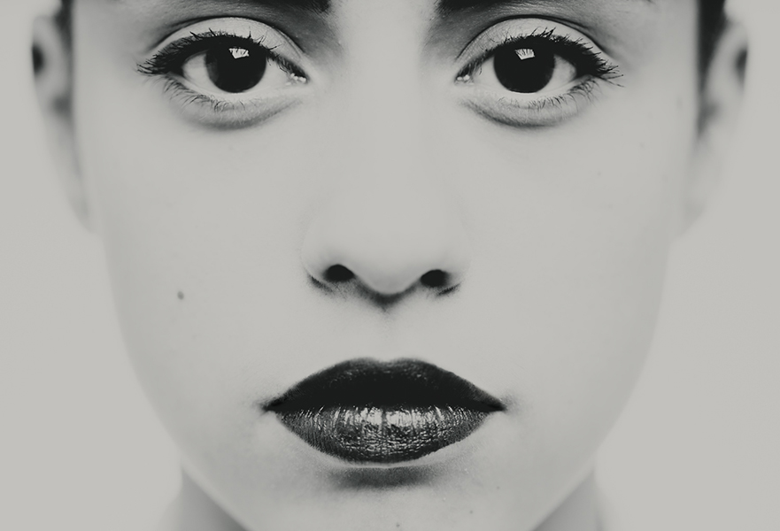 Photographie en très gros plan centrée sur les yeux et le regard, travail plastique sur l'intensité et la frontalité, détail d'un portrait en studio noir et blanc, réalisé à Bagnolet par le photographe, Nicolas Louis.