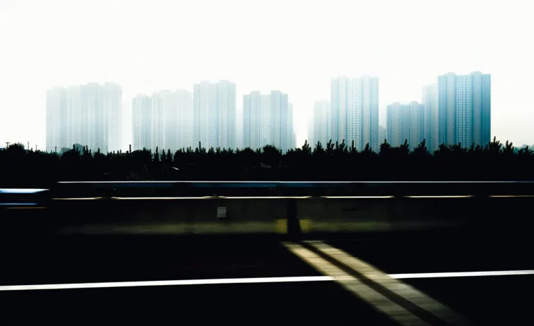 photographie de reportage, depuis l'autoroute à Pékin, montrant des barres d'immeubles, dans une atmosphère bleutée et vaporeuse.