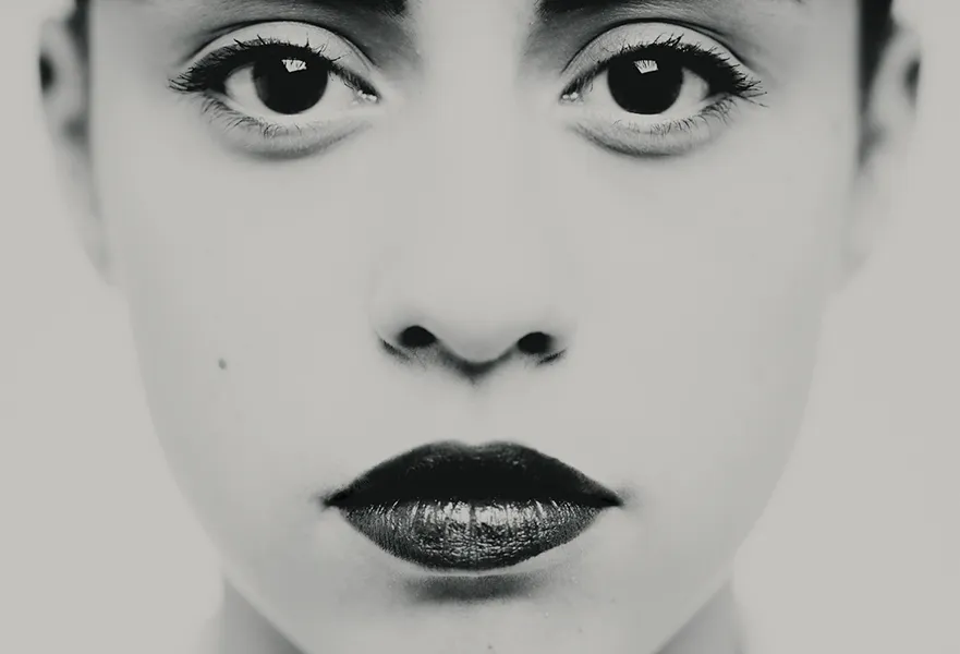 Photographie en très gros plan centrée sur les yeux et le regard, travail plastique sur l'intensité et la frontalité, détail d'un portrait en studio noir et blanc, réalisé à Bagnolet par le photographe, Nicolas Louis.