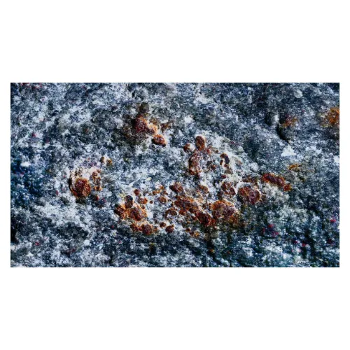 Version très macro et épurée de la série photo "Micro-territoires" réalisé en studio photo, d'une pierre de rue de couleur bleu-gris et granuleuse, montrant les taches de rouille texturées.