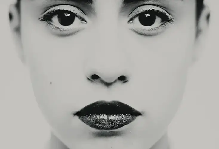 Photographie en très gros plan centrée sur les yeux et le regard, travail plastique sur l'intensité et la frontalité, détail d'un portrait en studio noir et blanc, réalisé à Bagnolet par le photographe, Nicolas Louis.