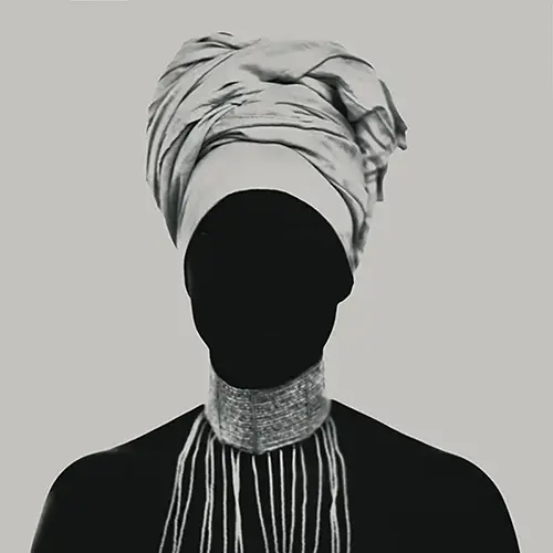 Photographie d'art en noir et blanc montrant la chanteuse Fafa Ruffino, en contre-jour total, visage masqué par l'ombre et surmonté d'un turban imposant, portant un collier de perles tombantes, studio photo, Le Vésinet par Nicolas Louis en 2016.